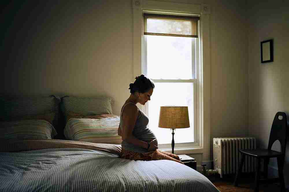 pregnant surrogate sitting on a bed