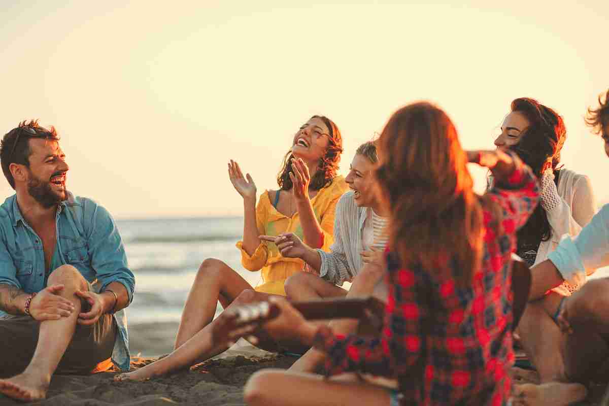 group of friends sitting on the beach laughing, having fun 11062b 97c897a7990f464cbe746d43928a2da7mv2